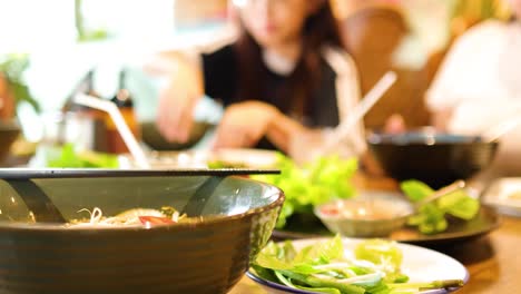 a lively dining scene in a vietnamese restaurant, capturing vibrant dishes and social interactions under warm lighting