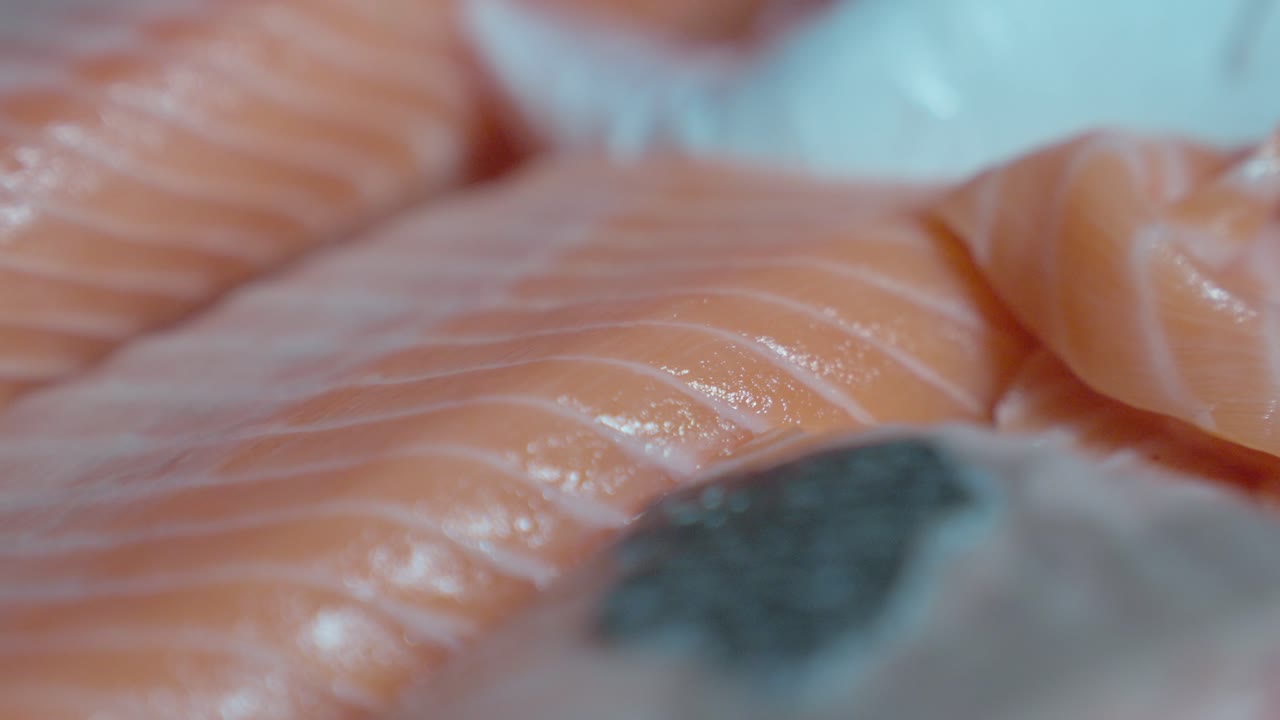 An up-close roaming shot showcasing a variety of raw fish, highlighting their fresh cuts, textures, and vibrant colors, ideal for sushi preparation or other seafood dishes.