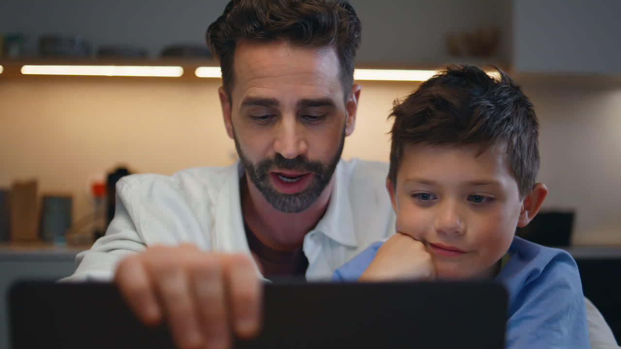 Positive dad son videocalling computer cozy interior closeup. Boy greeting hand