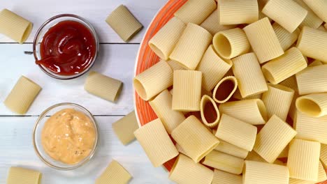 uncooked raw italian paccheri pasta rotating slowly on turntable in dish.