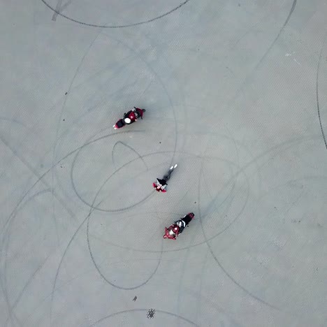 two motorcyclists are riding around woman which is laying on the pavement in the city. aerial view. camera motion down