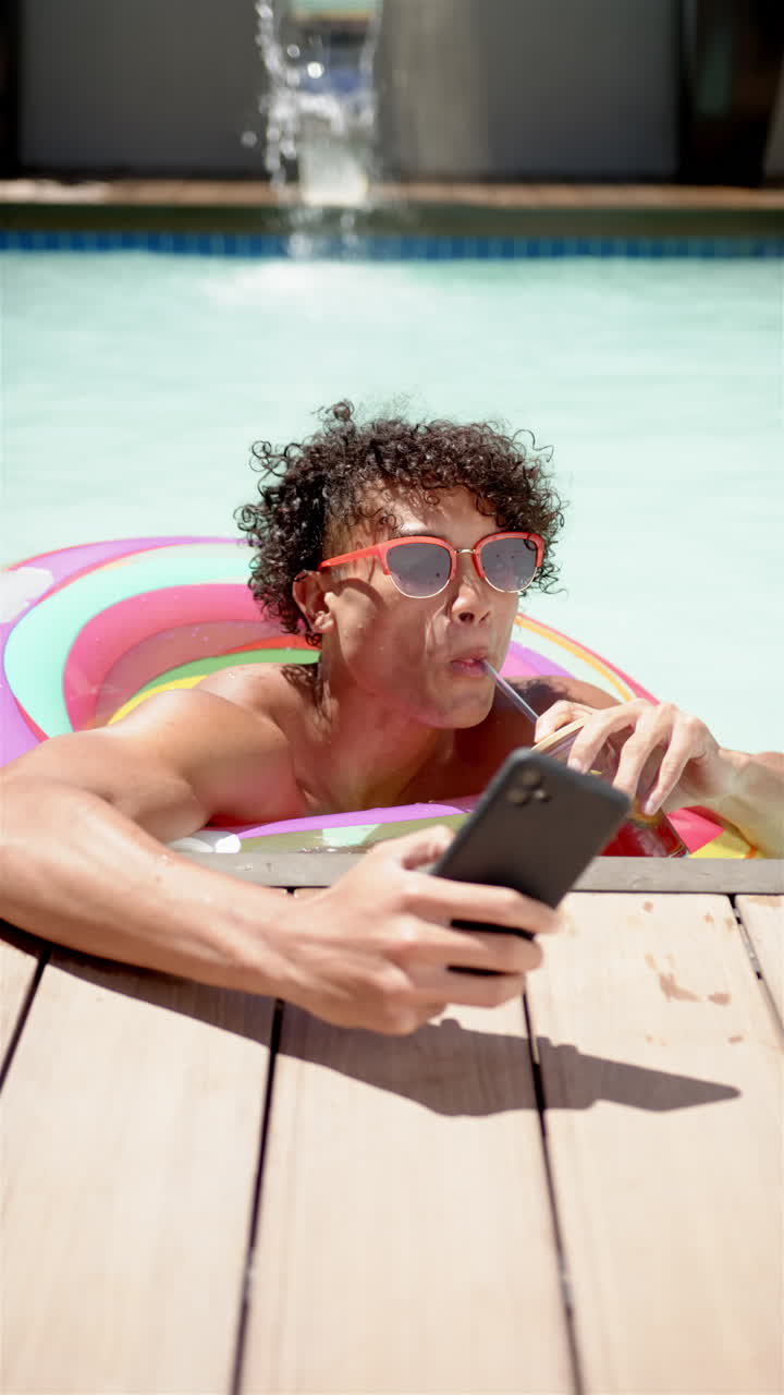 Vertical video: A young biracial person is taking a selfie in a pool