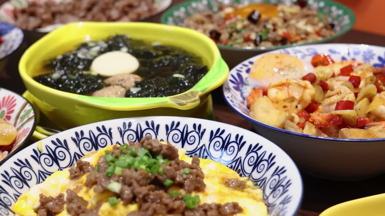 Colorful Thai rice meal with fried eggs, stir-fried vegetables, minced meat, and seaweed soup, captured in bright lighting with smooth camera movement