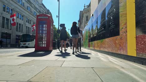 people walking by a telephone box and mural