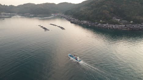 Paisaje-Del-Amanecer-De-La-Playa-Japonesa-De-Kyotango-Viaje-Aéreo-Drone-Destino-De-Viaje-De-Japón,-Cobertizos-Para-Botes-En-El-Entorno-Natural-Vista-De-Arriba-Hacia-Abajo-Sobre-El-Barco-De-Seguimiento