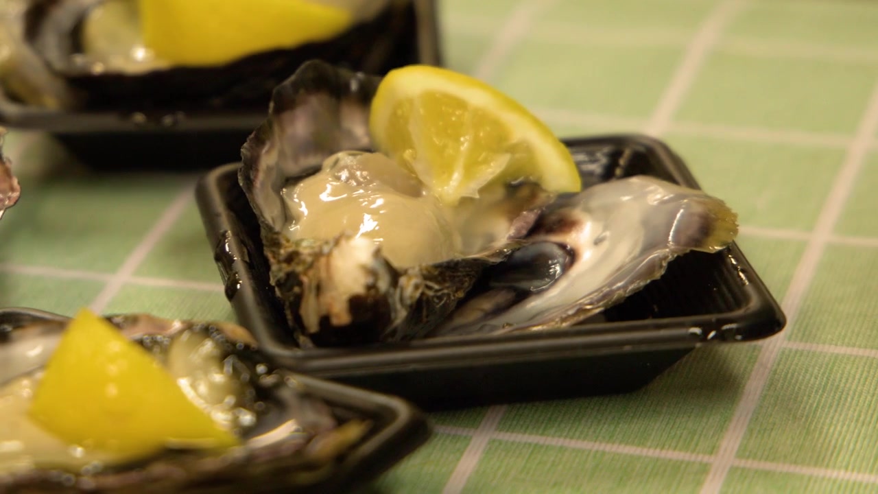 Close-up shot of a fresh raw oyster served with lemon on a green tablecloth