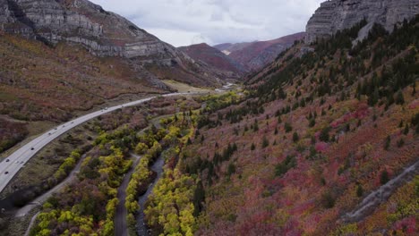 a highway road with cars driving in the valley between the mountains, aerial view