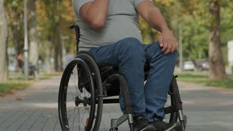 man with disabilities in wheelchair at the park alley use a smartphone