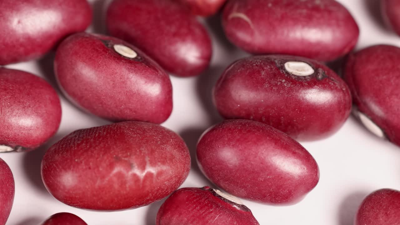 Detailed view of red beans arranged closely on a white background, showcasing their smooth texture and vibrant color.