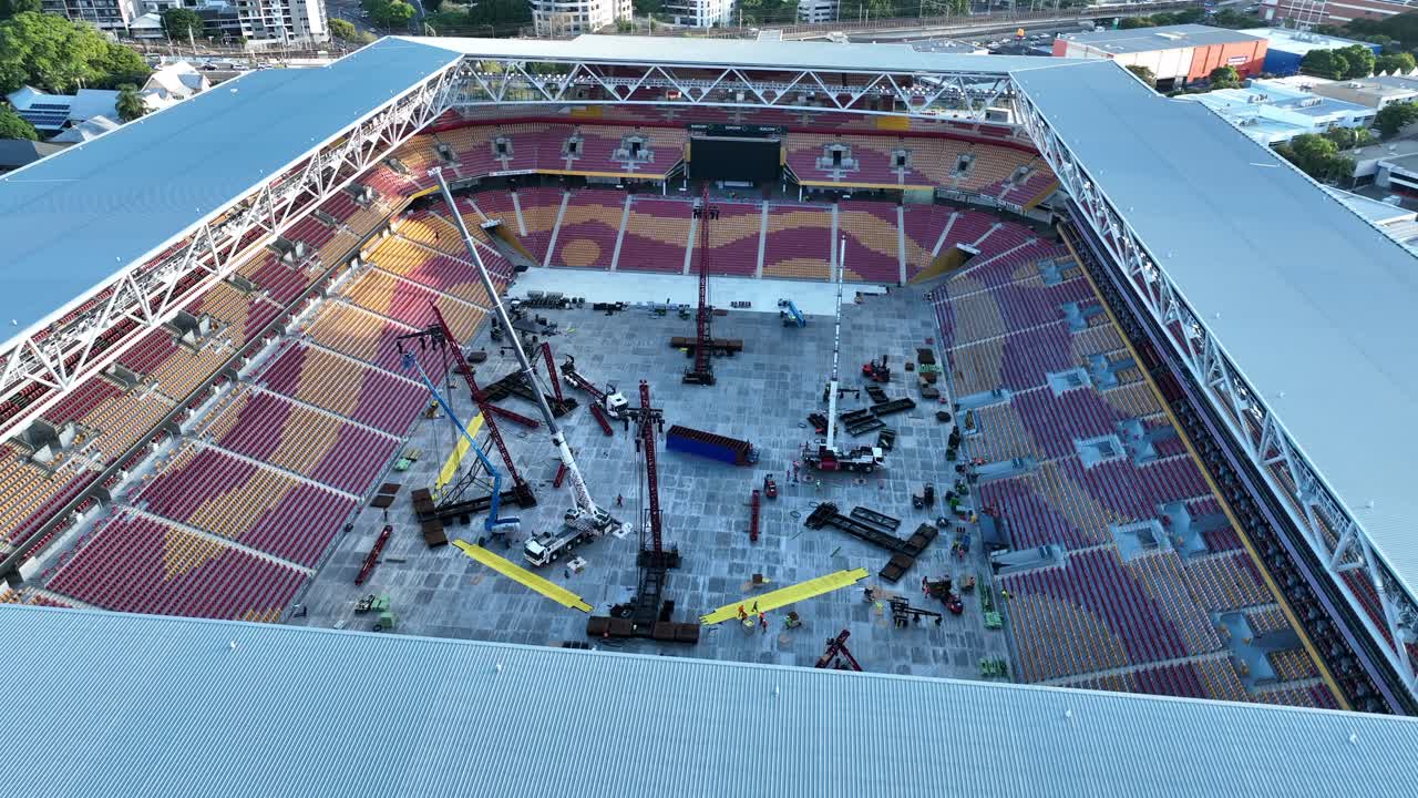 disparos de drones volando alrededor del estadio suncorp, con vistas aéreas mirando hacia el interior del estadio donde los trabajadores están convirtiendo la arena para albergar un concierto de música