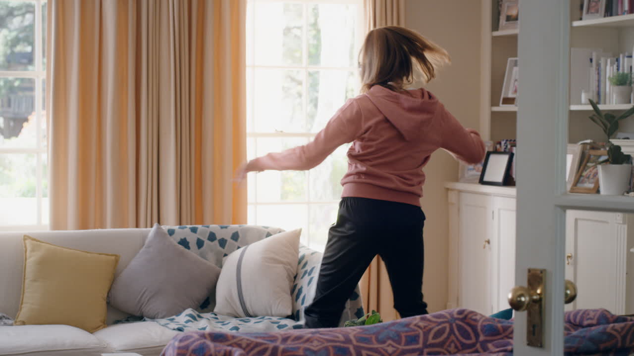 멋진 십대 소녀가 헤드폰을 착용하여 춤을 추고 음악을 듣고 재미있는 십대 소녀가 집에서 미친 춤 움직임으로 축하하고 주말에 자유를 즐기고 4k