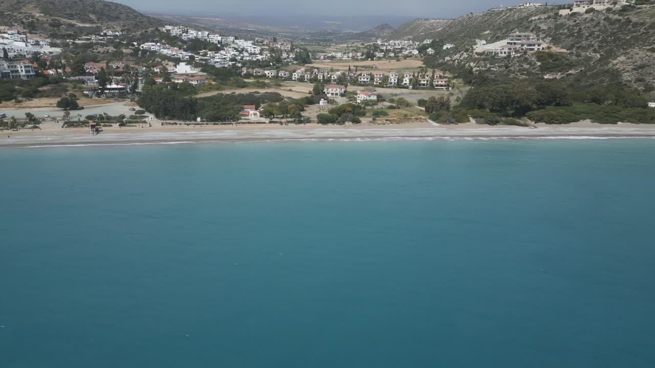playa de pissouri en chipre, con aguas claras de color turquesa y el telón de fondo de la ciudad costera, vista aérea
