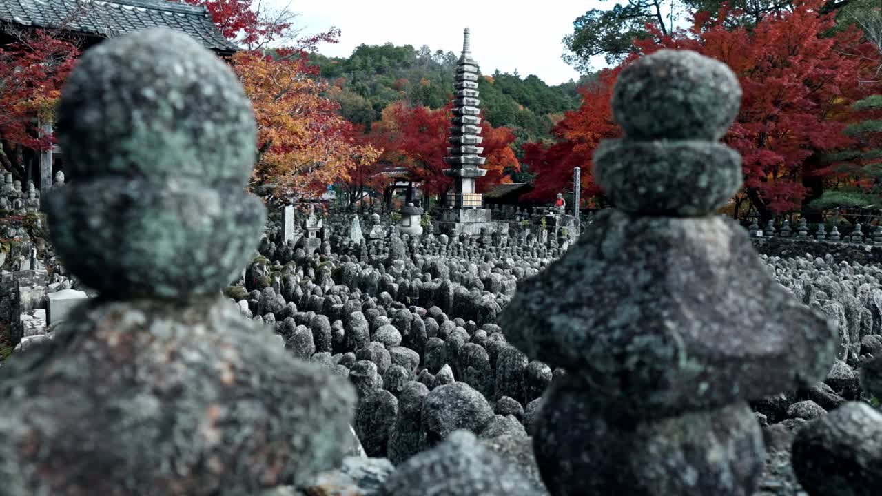 A stunning view of a traditional temple in Arashiyama, Kyoto, surrounded by vibrant red and orange autumn foliage.