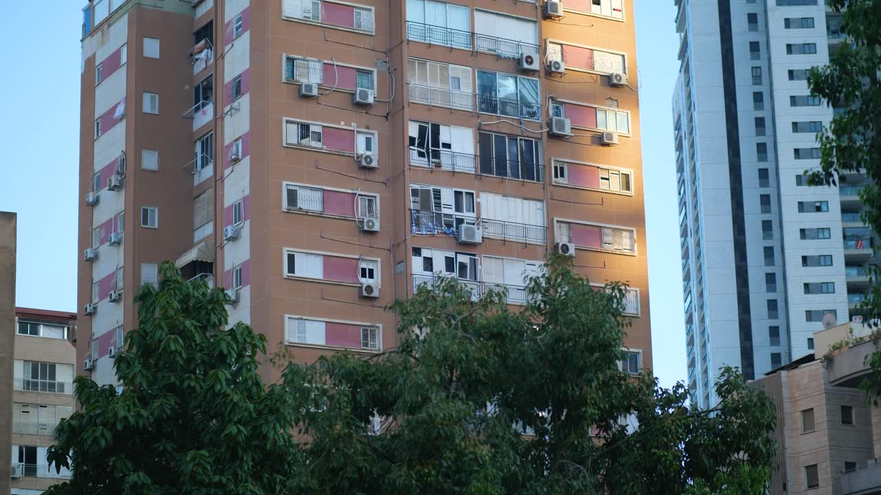Low angle shot of an apartment building in Tel Aviv with shattered windows and visible impact damage after an Iranian missile strike