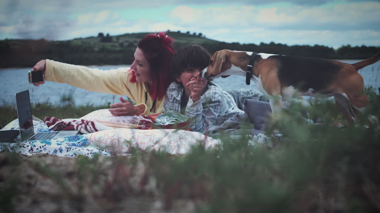 4K Mamma, figlio e cane che si rilassano in spiaggia.