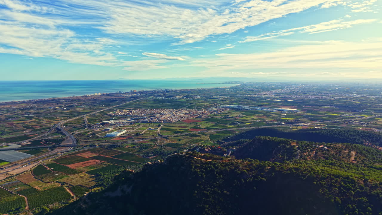晴れた日の海岸風景。澄みきった空の下、畑や道路が広がり、遠くには街並みが望めます。