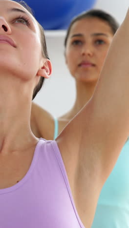 fit women doing yoga together in studio