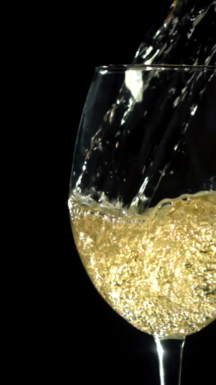 Vino bianco dorato versato in un bicchiere al rallentatore