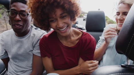 Group-Of-Young-Friends-In-Back-Of-Open-Top-Hire-Car-On-Summer-Vacation