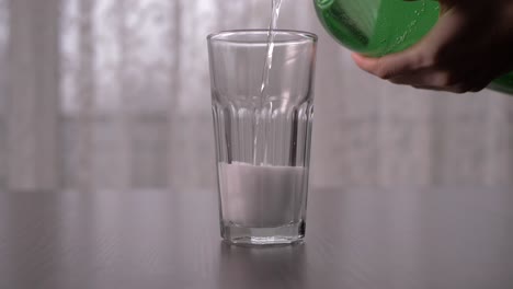 Verter-Soda-Espumosa-Transparente-En-Un-Vaso-Alto-En-Cámara-Lenta,-Toma-Directa