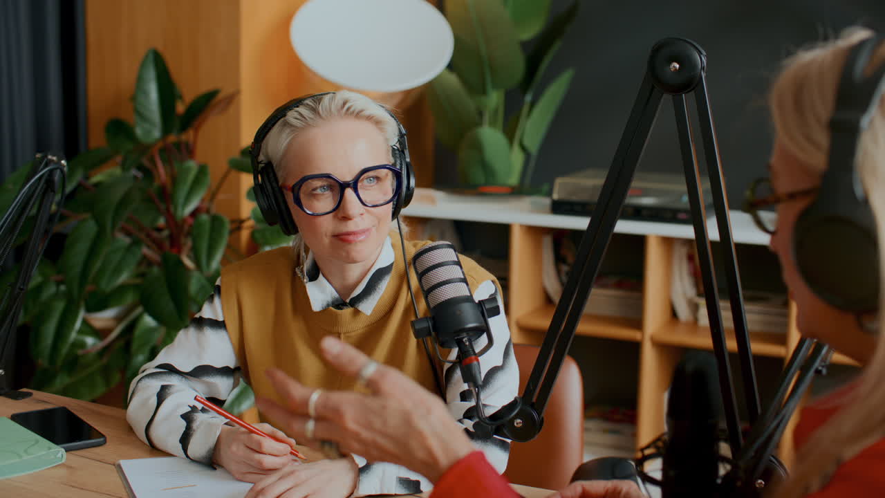 Female Podcast Host Speaking with Guest during Recording Session in Studio