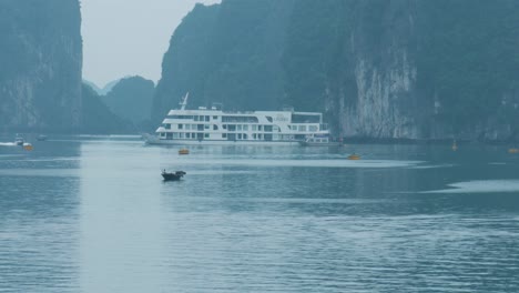 Scenic-Speed-Boat-going-through-Ha-Long-Bay-with-Rocky-Mountains-and-Cruise-Ship-at-the-background