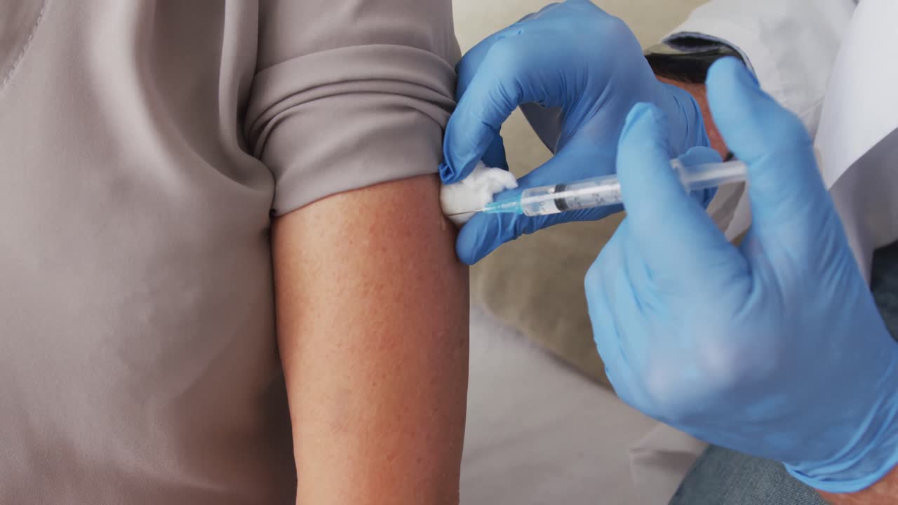 집에서 여성에게 코로나19 백신을 투여하는 남자 의사의 클로즈업