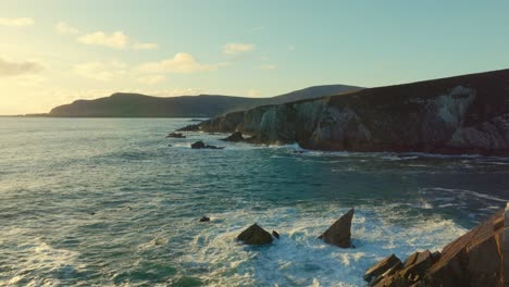 Drone-flying-parallel-to-the-scenic-coastline-of-the-White-Cliffs-of-Ashleam-during-sunset