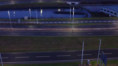 Aerial-view-modern-illuminated-quiet-highway-lanes-road-intersection-traffic-pan-left-following-van