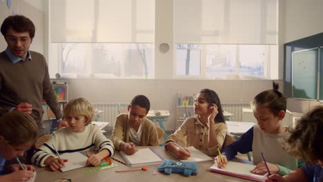 Profesor-Explicando-La-Lección-A-Los-Escolares.-Estudiantes-Escribiendo-En-Cuadernos-De-Ejercicios