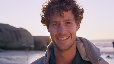 Portrait-of-attractive-man-smiling-on-beach-at-sunset-in-slow-motion