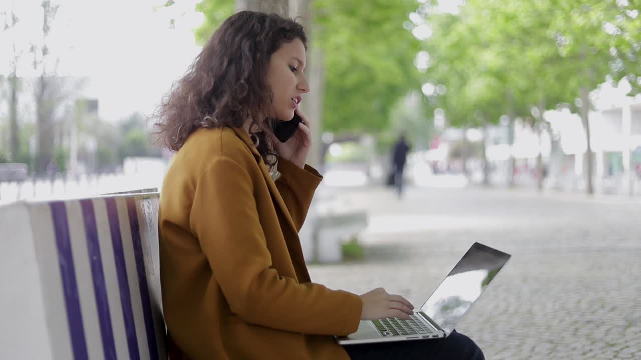 Woman using smartphone and laptop outdoor