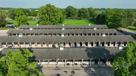 Aerial-view-of-a-long-stable-complex-at-Kentucky-Horse-Park,-with-lush-greenery-surrounding