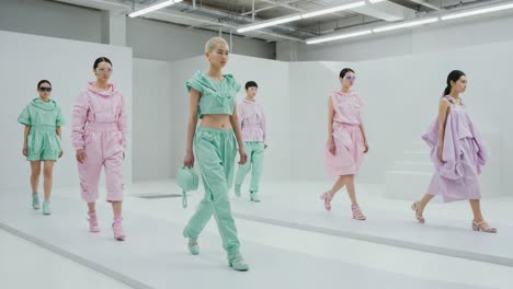 impressive fashion show featuring stylish models in colorful, contemporary outfits walking down the runway in a minimalist white set design