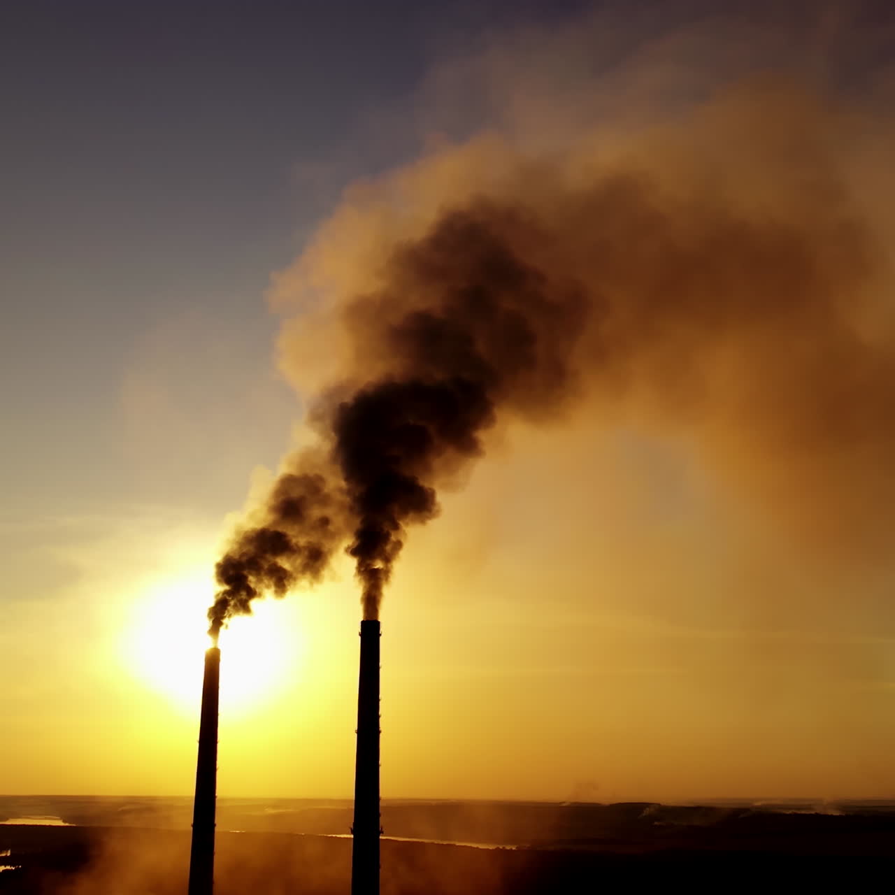 Dark smoke from factory. Industrial pipes of manufacture pollute the atmosphere at sunset. Toxic smoke in the air. Ecological problems.