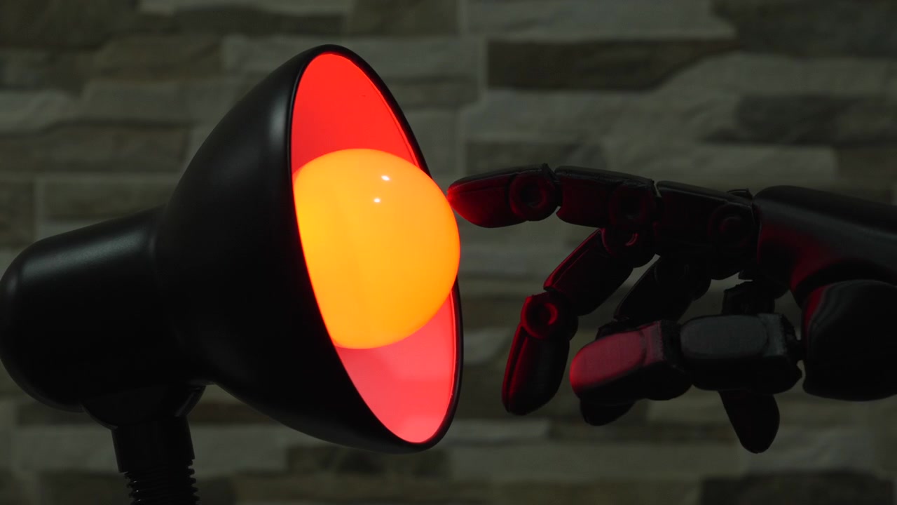 Mano robotica nera o protesi si protende verso una lampadina gialla luminosa in una moderna lampada da scrivania contro un muro di pietra, utile per concetti di intelligenza artificiale (AI), innovazione e tecnologia per la casa intelligente.