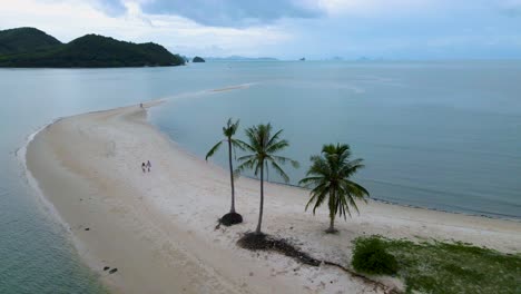couple of men and women walking on the beach at the island koh yao yai thailand, beach with white sand and palm trees.