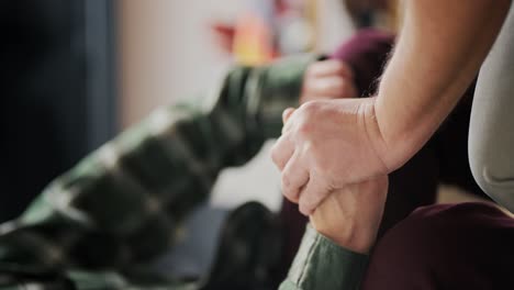 video de primer plano vertical de un hombre de mediana edad con una camisa a cuadros sosteniendo de la mano a su novio anciano mientras está sentado en un sofá en un apartamento moderno. pareja lgbt de dos hombres tomados de la mano durante una conversación difícil y resolviendo problemas como pareja