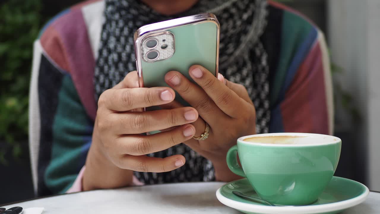 mujer usando su teléfono mientras bebe café en una cafetería