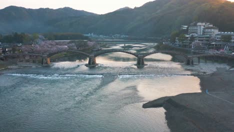 4k-Aerial-View-Kintai-Bridge-and-Iwakuni-at-Dawn,-Spring-Sakura-Season,-Japan