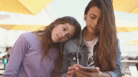 two teenage friends share headphones and listen to music from the same device