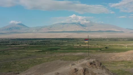 aerial drone shot zoom out shot of flag waving on the hill in armenia