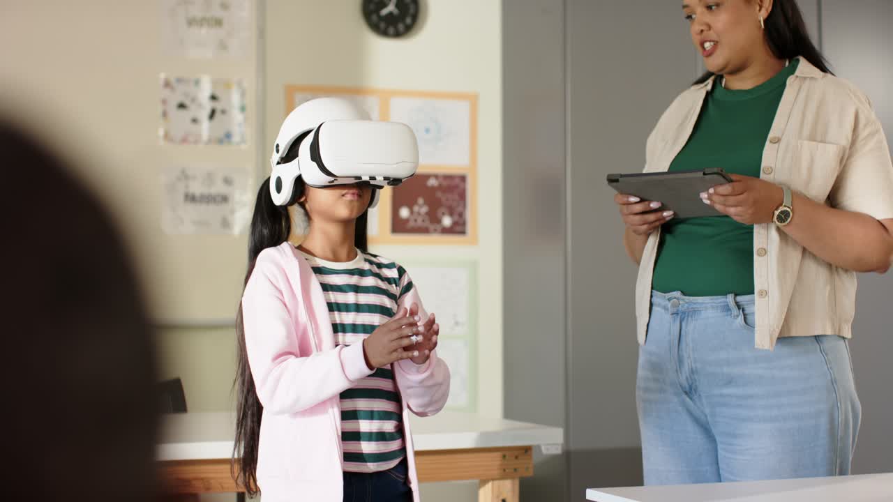 African American teacher reading tablet, youth girl wearing white VR headset gesturing in classroom