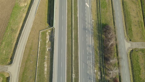 Aerial-tilt-up-shot-of-rural-area-with-many-cars-driving-on-modern-asphalt-highway-in-Poland-during-bright-sunny-day
