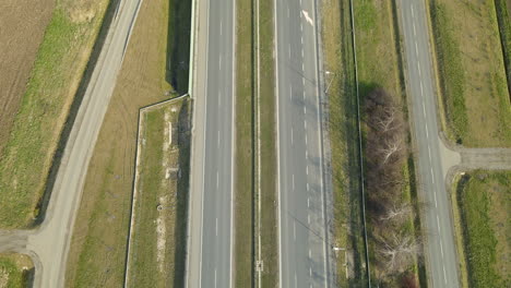 aerial tilt up shot of rural area with many cars driving on modern asphalt highway in poland during bright sunny day