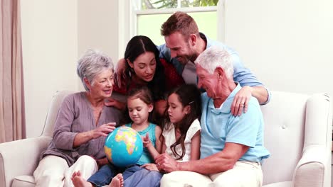 smiling family on sofa looking at globe