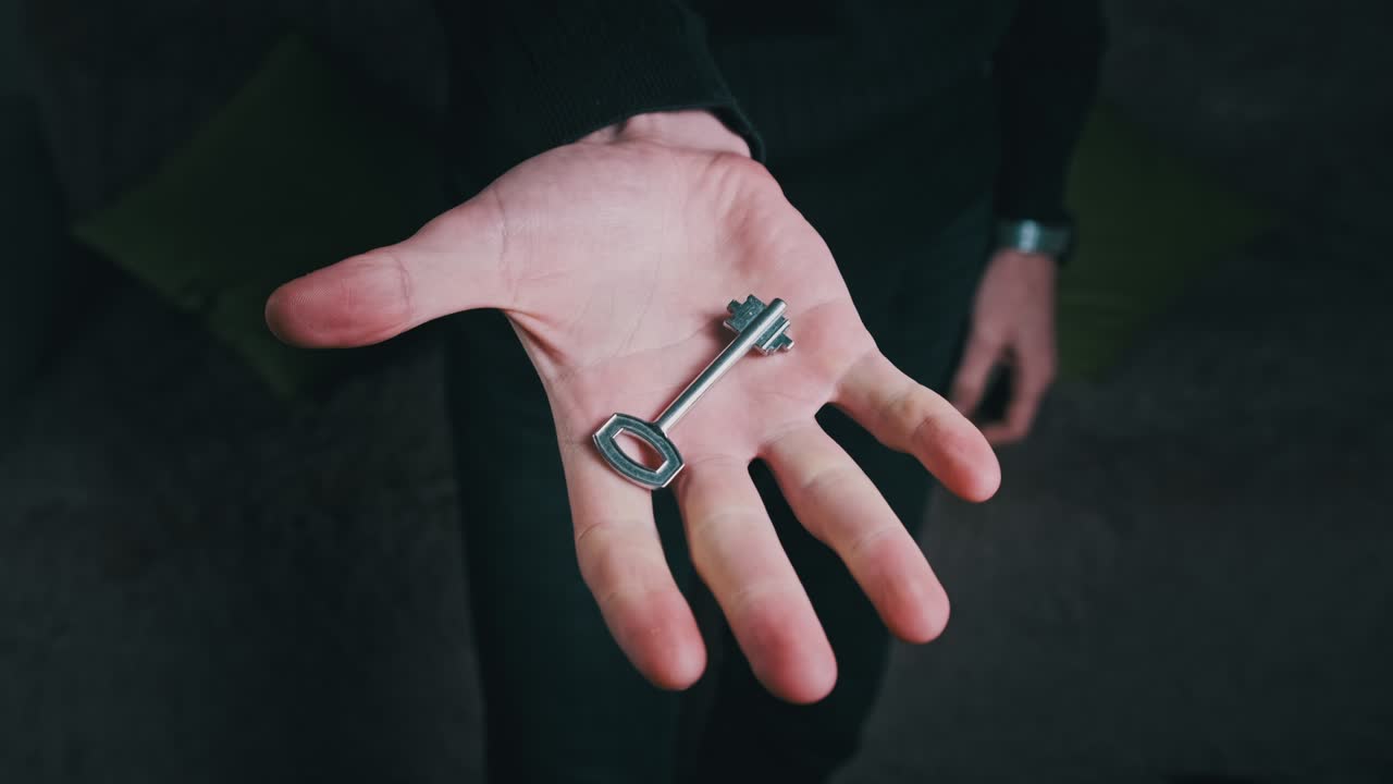 мужская рука, держащая ключ от дома и показывая его камере, крупный план