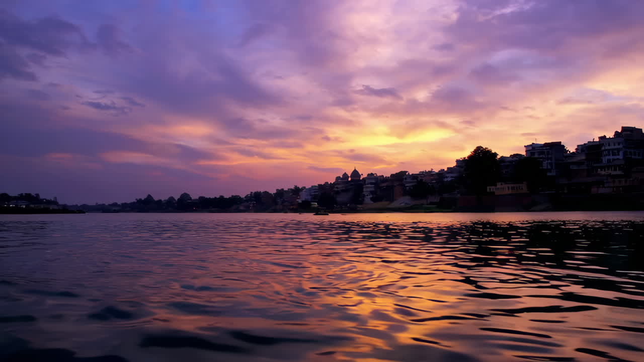Vibrant Sunset Reflections on the Ganges River with a Distant Cityscape