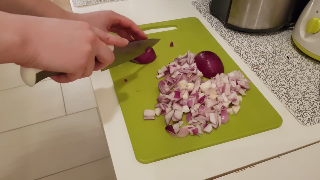 Caucasian woman cooking and cutting up purple onion