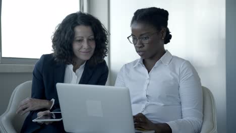 smiling businesswomen with laptop and tablet pc